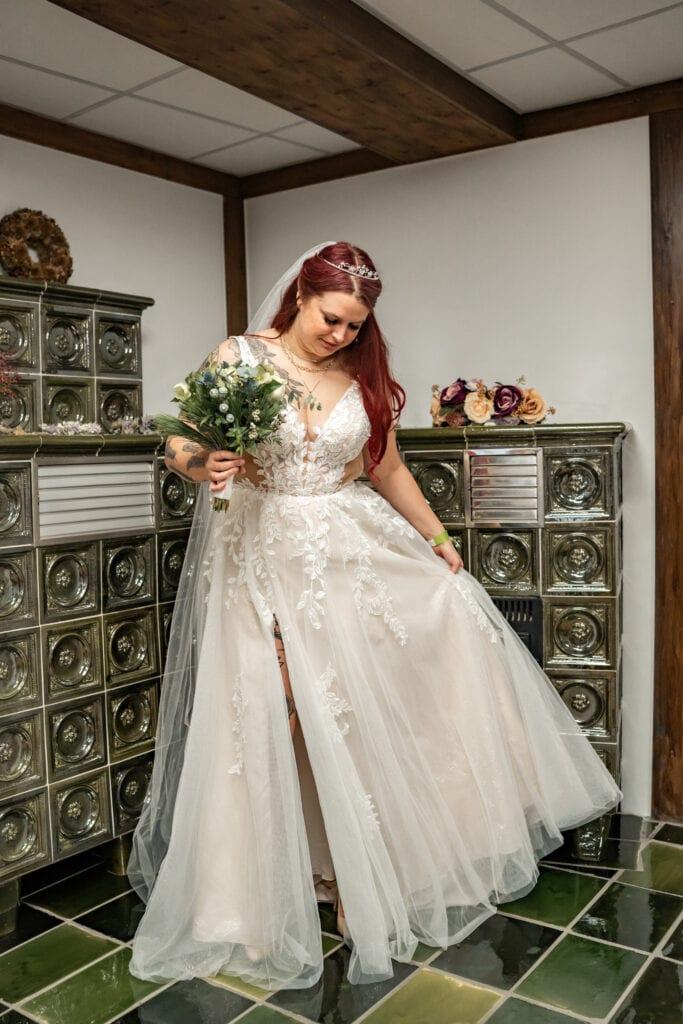 Braut im weißen Kleid neben Kachelofen