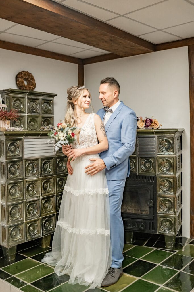 Brautpaar vor einem traditionellen Kachelofen