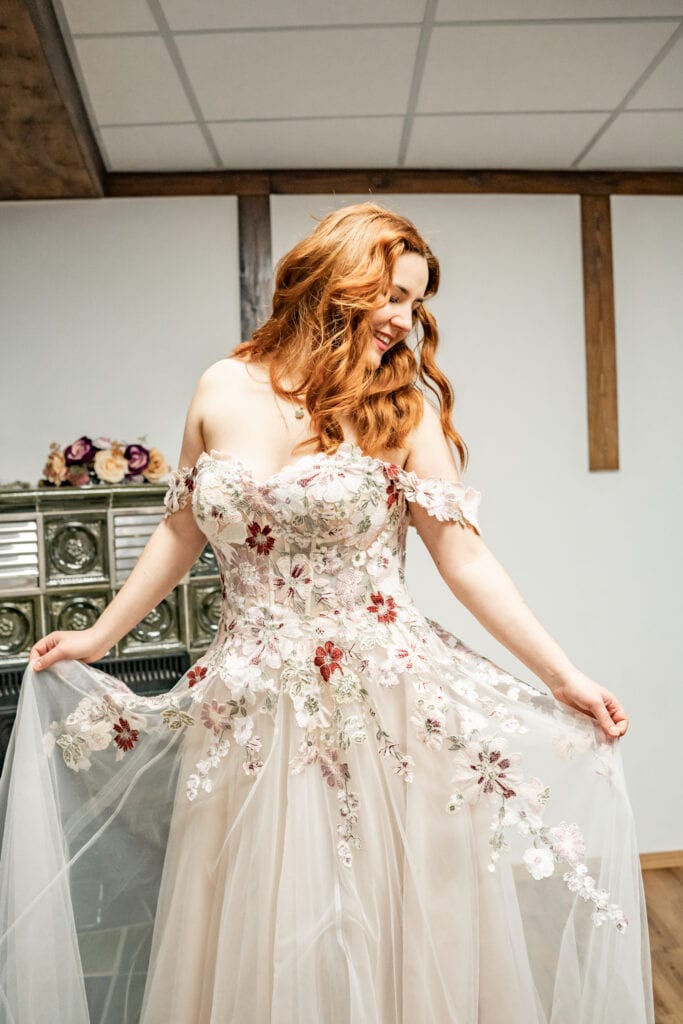 Braut in floraler Spitzenrobe lächelnd