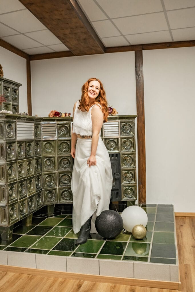 Frau in Weiß lächelt vor altem Ofen