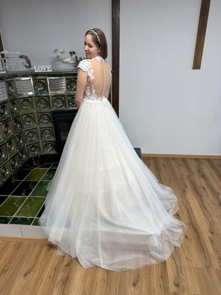 Braut in weißem Kleid vor Ofen