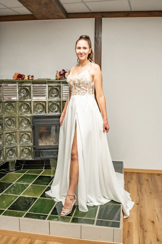 Frau im eleganten weißen Kleid neben Ofen.