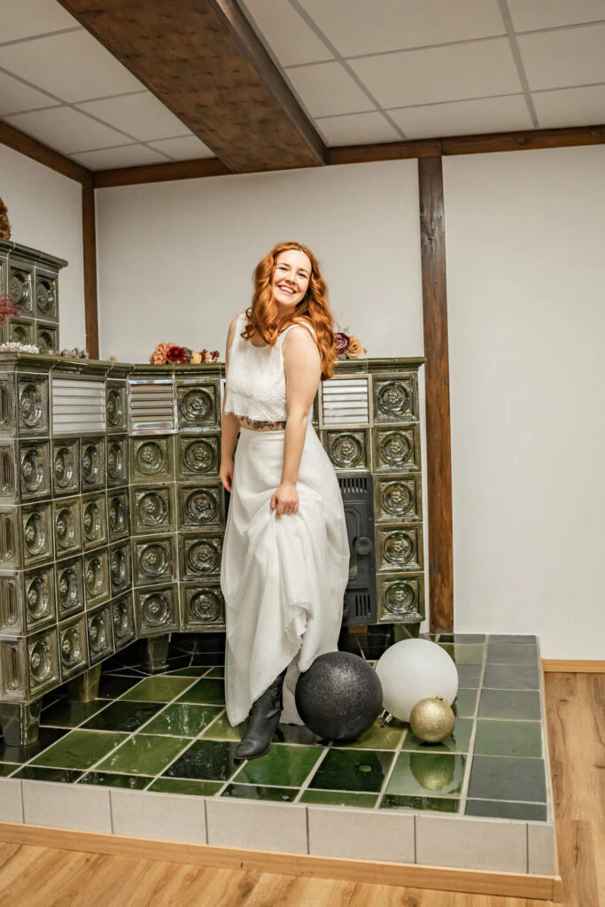 Frau in Weiß lächelt vor altem Ofen